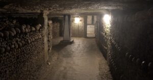 Hallway lined with bones, at the end of which is a pillar painted with an obelisk