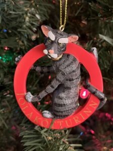 Ornament of a gray cat sitting in a red circle